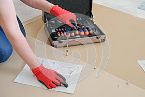 Middle aged woman hands assembling furniture at home. Woman using screwdriver while sitting on floor in apartment and