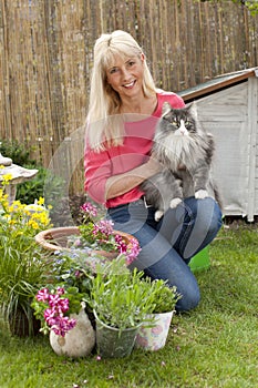 Middle aged woman with her cat in her garden