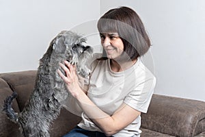 Middle-aged woman with her cute dog plays at home. A woman hugs her beloved dog. Dog training.