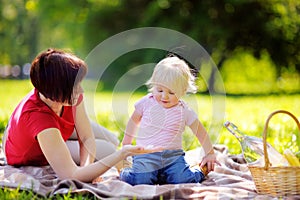 Middle aged woman and her little grandson having a picnic in park