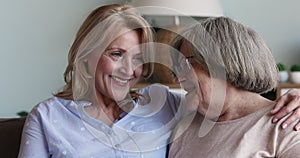 Middle-aged woman her older mother talking sit on sofa