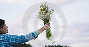 Middle-aged woman holding bouquet of wildflowers in hand