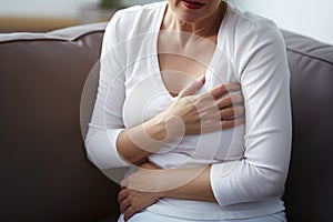 Middle-aged woman holding hands to chest in pain. Concept for heartache or cardiac arrest