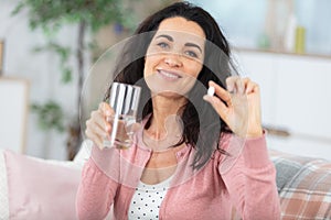 middle aged woman holding medication and glass water