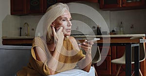 Middle-aged woman holds smartphone having conversation on speakerphone