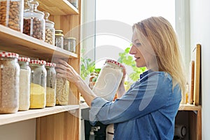 Middle aged woman at home in kitchen in pantry