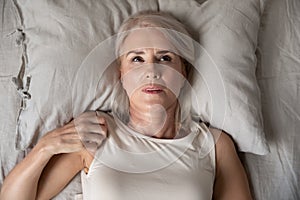 Middle aged woman insomniac lying awake in bed, top view