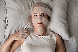 Middle aged woman insomniac lying awake in bed, top view photo