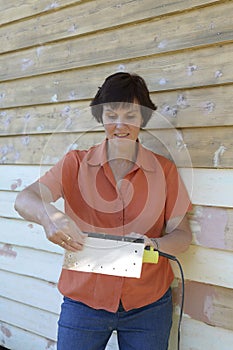 Middle-aged Woman Inspecting Electric Sander.