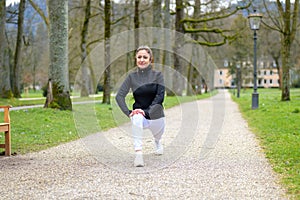 Middle-aged woman limbering up doing stretch and lunge exercises