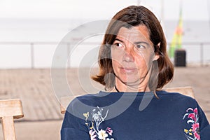 Middle-aged woman look aside into the distance while sitting on a summer terrace cafe beach