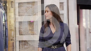 Middle aged woman looking in shop window with fashionable clothes outdoors