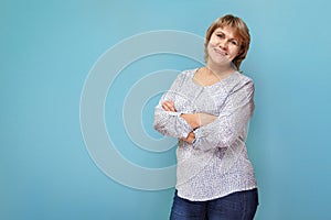 A woman in a blouse and jeans stands on a blue green background
