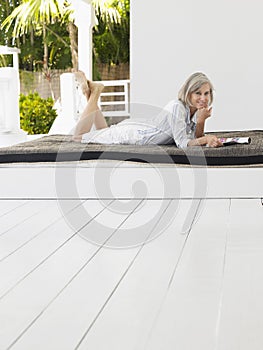 Middle Aged Woman Lying On Daybed On Verandah