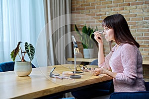 Middle-aged woman with make-up mirror cosmetics doing makeup at home