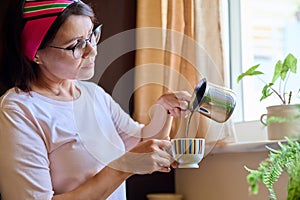 Middle aged woman making coffee, pouring from a cezve turk into a cup.