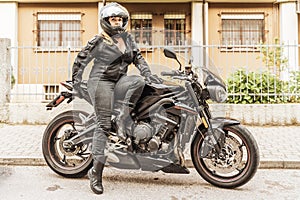 middle aged woman in motorbiker clothing riding a motorcycle outdoors