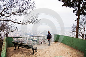 Middle aged woman with panoramic city view from Mtatsminda hill, Tbilisi, Georgia