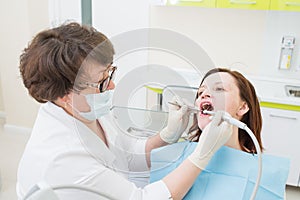 Middle aged woman patient at the dentist drilling the tooth with a turbine and making dental fillings