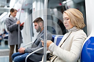 Middle aged woman with phone in metro car