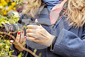 A middle-aged woman photographer takes pictures of spring flowers in the botanical garden