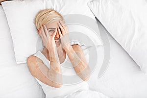 Middle aged woman playfully hiding her eyes behind her hands