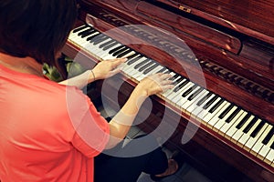 Middle aged woman playing piano back view