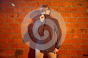 A middle-aged woman poses showing clothes near red brick wall. An inept model in an inept shoot photo