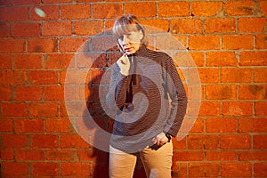 A middle-aged woman poses showing clothes near red brick wall. An inept model in an inept shoot photo