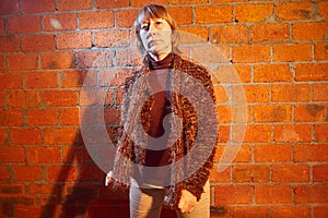 A middle-aged woman poses showing clothes near red brick wall. An inept model in an inept shoot photo