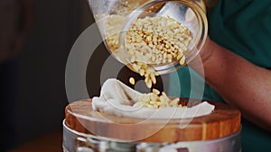 Middle aged woman pours pine nuts into oil extractor closeup