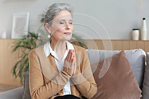 Middle aged woman praying, eyes closed, looking up, hoping for best, asking for forgiveness
