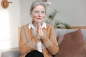Middle aged woman praying, eyes closed, looking up, hoping for best, asking for forgiveness