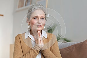 Middle aged woman praying, eyes opened, looking up, hoping for best, asking for forgiveness