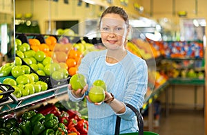 Middle-aged woman purchaser buying fresh apples in grocery store