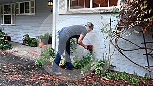 Middle aged woman putting a foam cover on an outdoor spigot as part of fall outdoor chores getting ready for winter