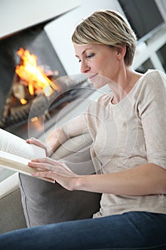 Middle-aged woman reading book at home