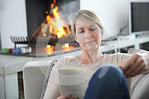 Middle-aged woman reading book at home