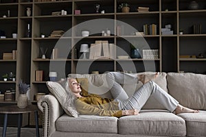 Middle-aged woman relaxing on cozy sofa in living room