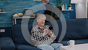 Middle aged woman relaxing holding smartphone reading news