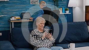 Middle aged woman relaxing holding smartphone reading news