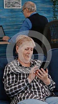 Middle aged woman relaxing holding smartphone reading news