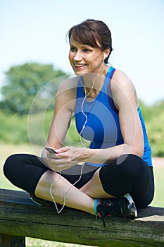 Middle Aged Woman Relaxing With MP3 Player After Exercise