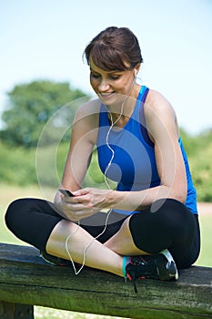 Middle Aged Woman Relaxing With MP3 Player After Exercise