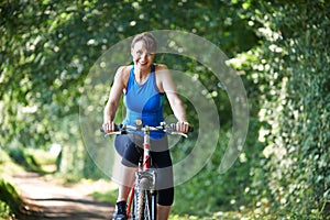 Middle Aged Woman Riding Bike Through Countryside