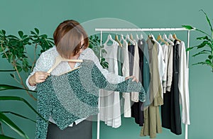 Middle aged woman shopping new dress clothes shelf green