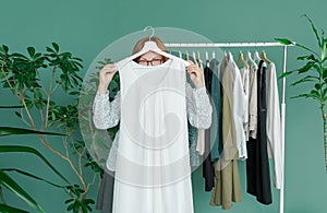 Middle aged woman shopping new dress clothes shelf green