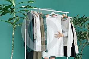 Middle aged woman shopping new dress clothes shelf green