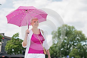 middle-aged woman with a short haircut with an umbrella protecting from sun