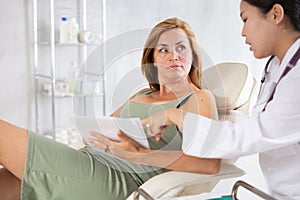 Middle-aged woman signing contract before having a medical operation in cosmetology clinic